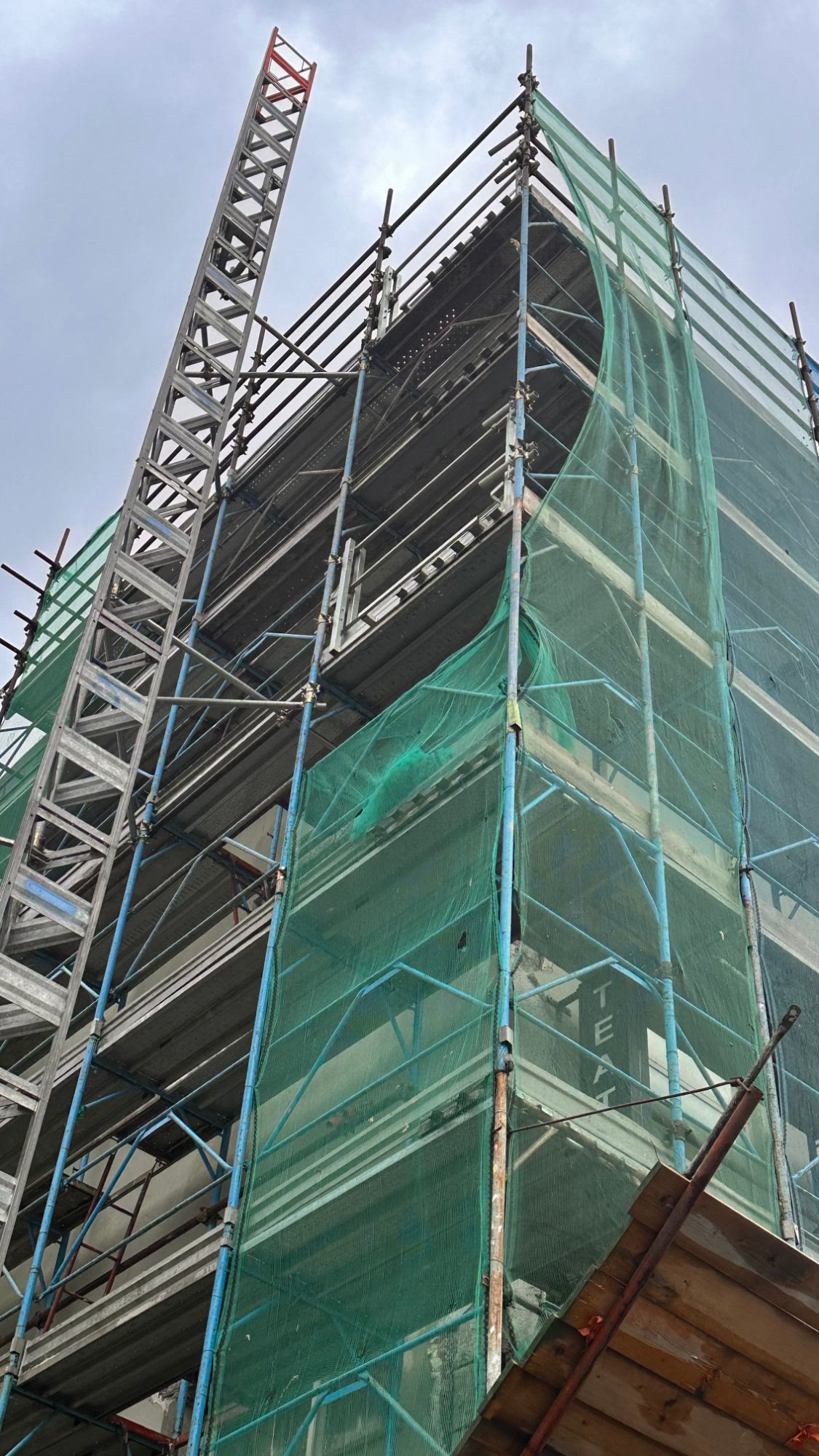 Il ponteggio con le reti verdi e l’elevatore di cantiere visti dal basso