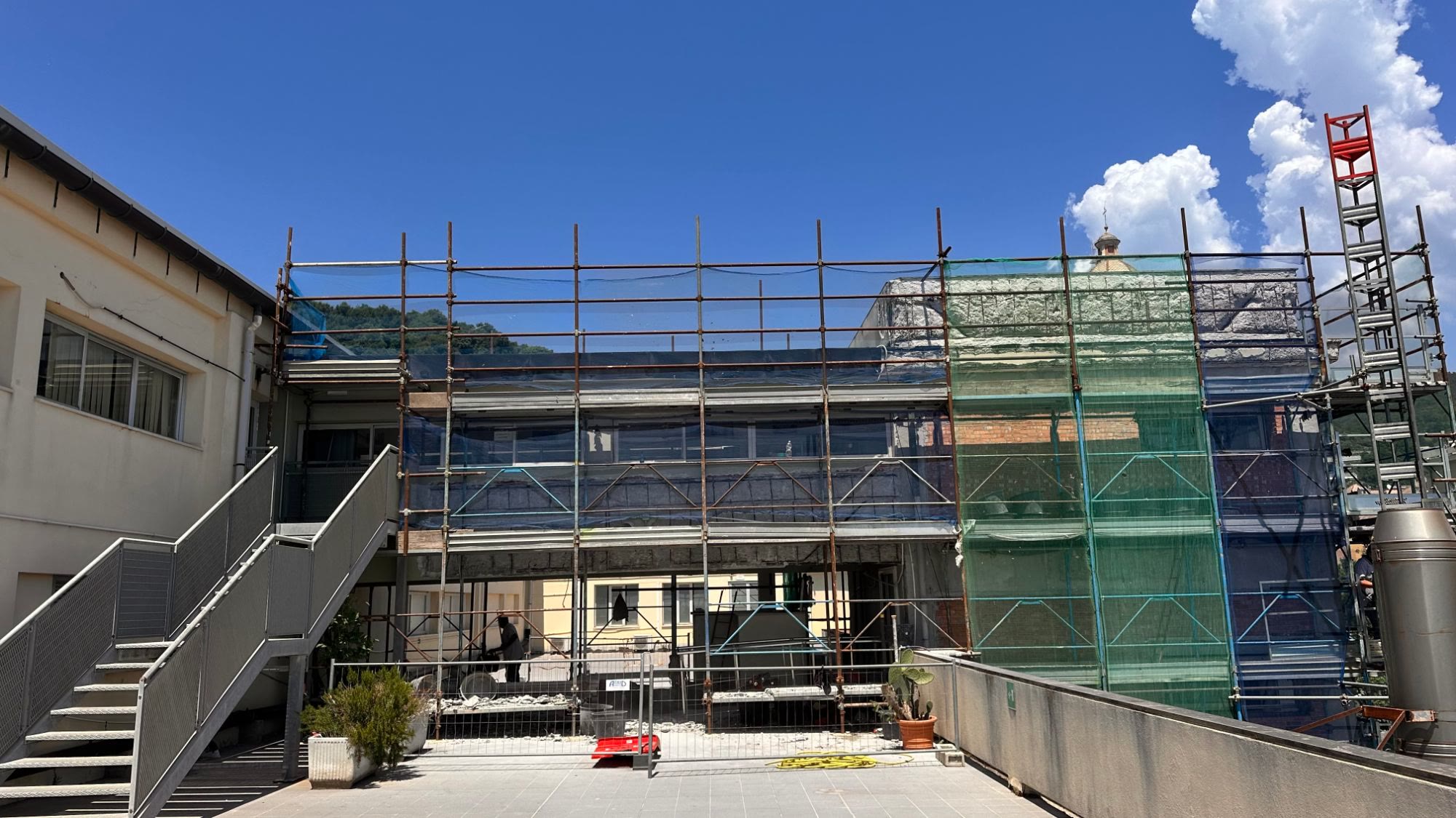 Il vano scala coperto dal ponteggio con le reti, nel cortile della biblioteca