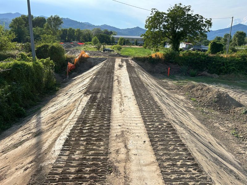 Il rilevato dell’argine appena compattato, con i segni dei cingoli, fra la vegetazione e i campi
