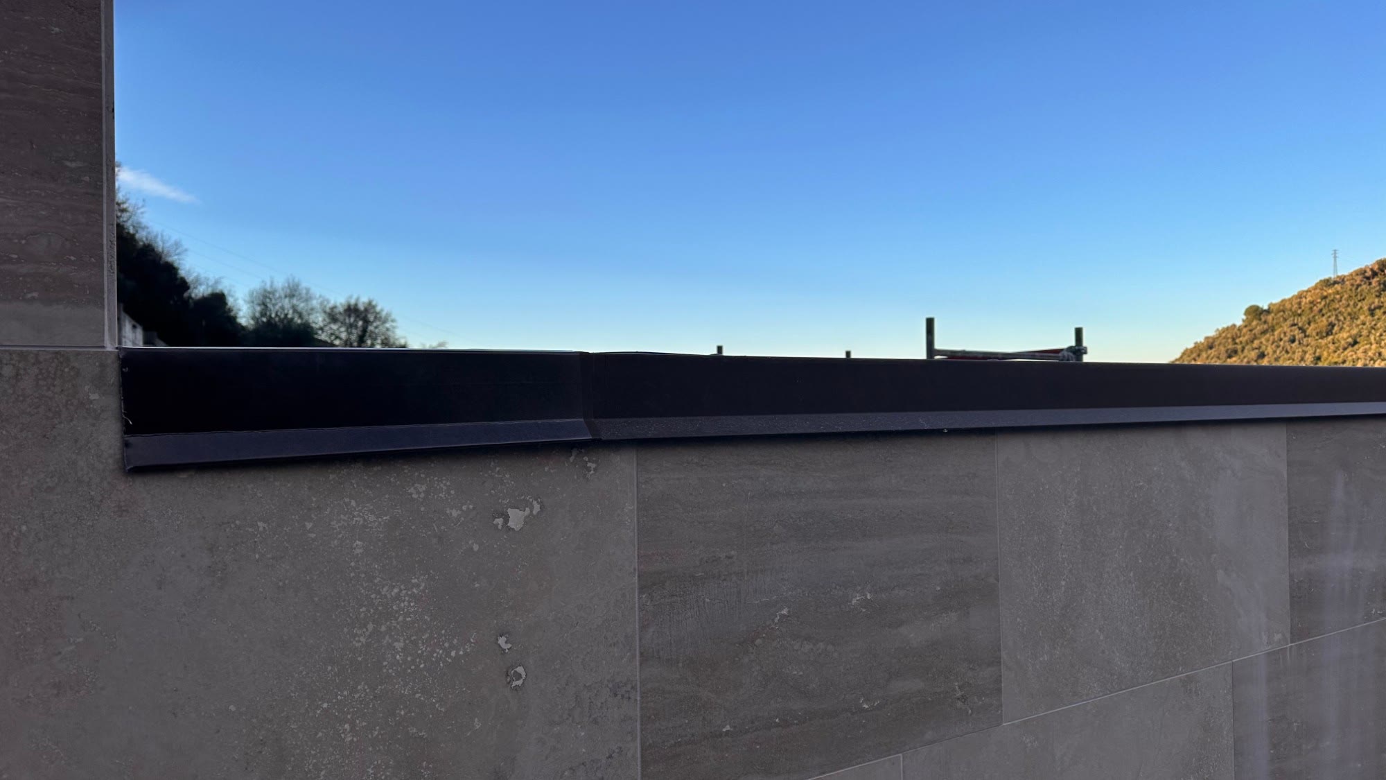 Il rivestimento in lastre di pietra dei nuovi loculi, con la scossalina scura sulla sommità