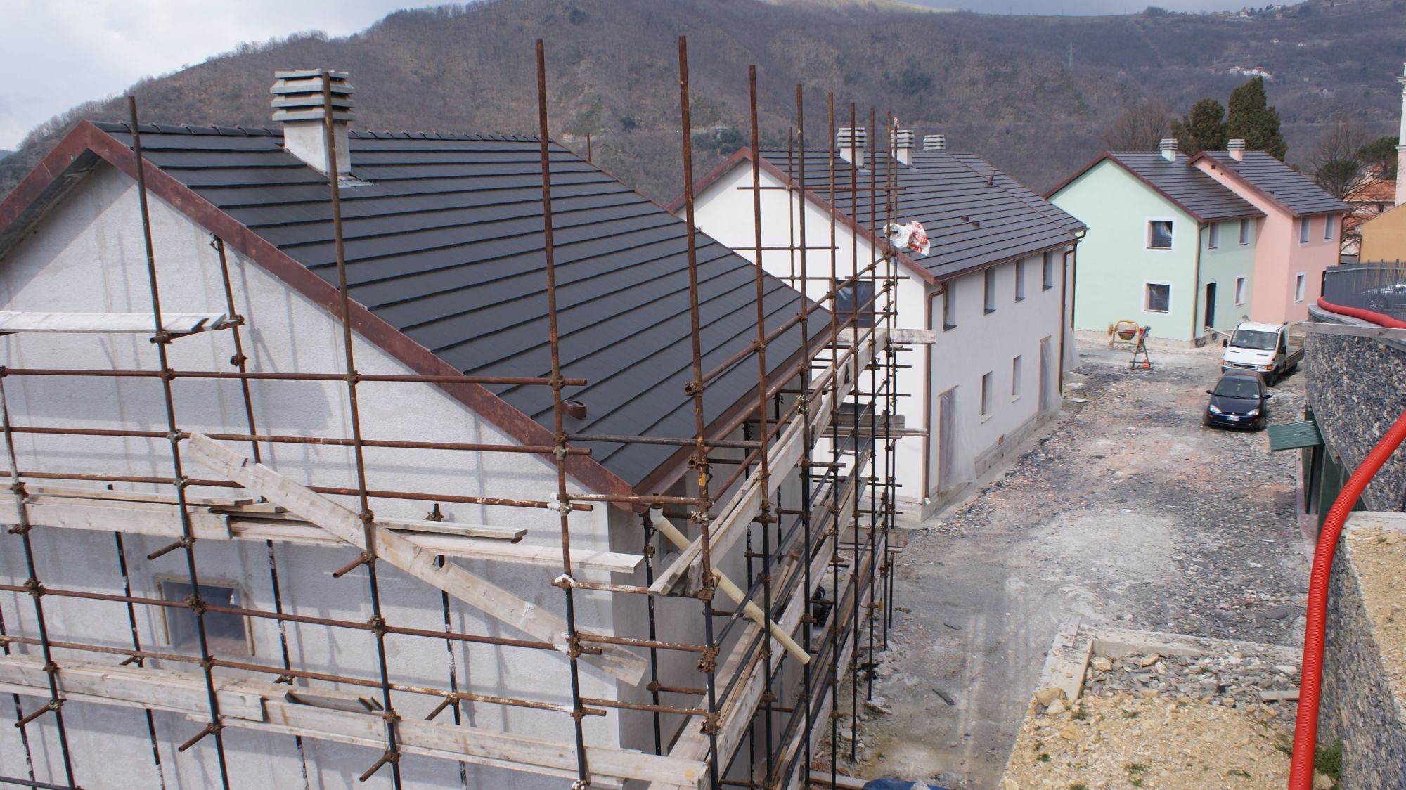 Le palazzine coperte e intonacate, con i ponteggi ancora montati sulla prima; in fondo due case già tinteggiate di verde e di rosa