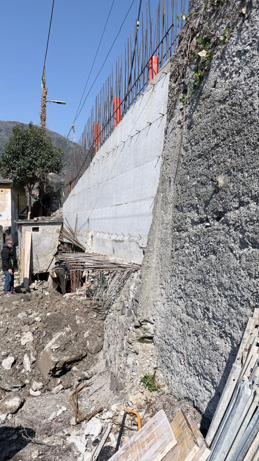 Il nuovo muro in cemento armato con le casseforme appena tolte e i ferri di ripresa per il parapetto, accanto al vecchio muro in pietra