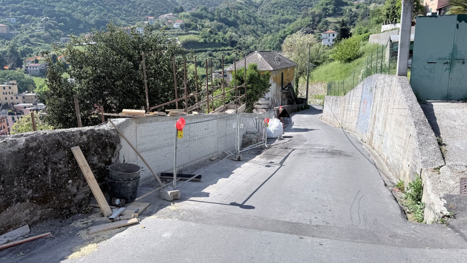 La strada riaperta con il muro nuovo e il parapetto, ancora con le recinzioni di cantiere