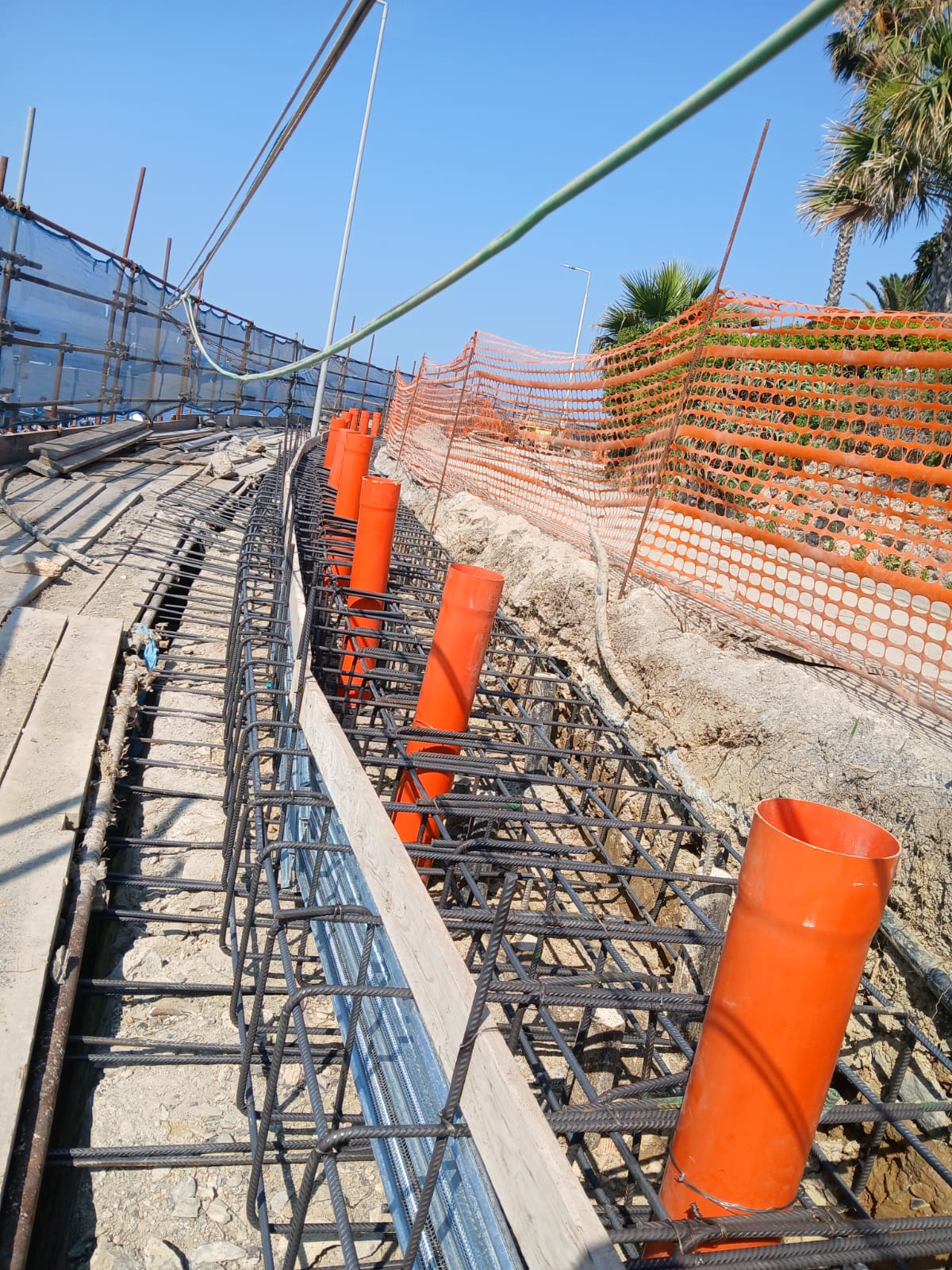 Armatura di un cordolo in cemento armato con una fila di tubi arancioni inseriti fra i ferri