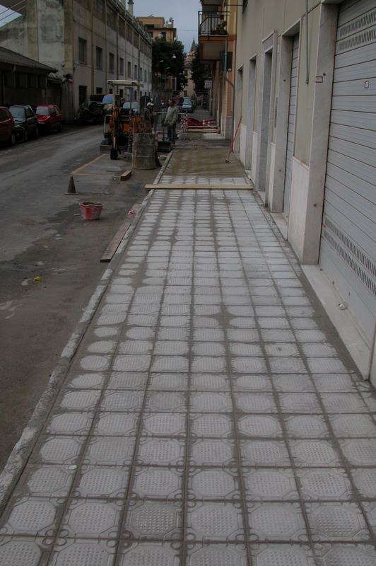 Marciapiede rifatto in piastrelle di cemento decorato lungo una via cittadina