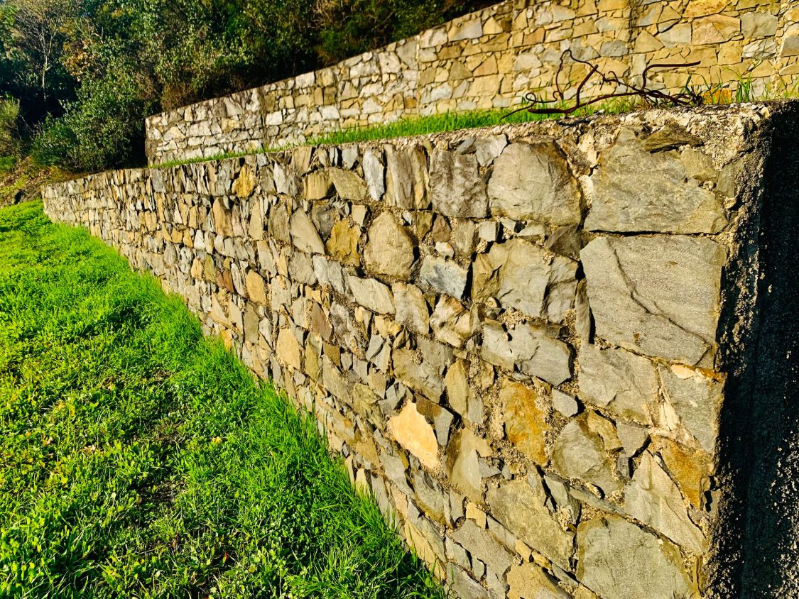 Muri di contenimento in pietra su più livelli, con il prato alla base