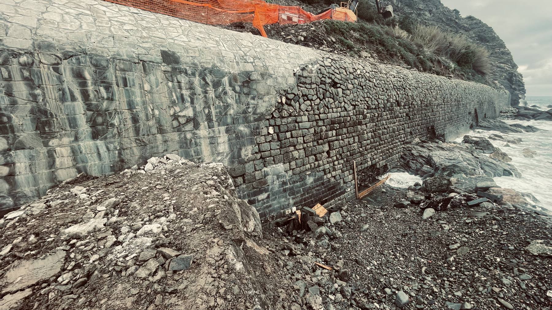 Il muro ciclopico rivestito in pietra a picco sul mare, con la scogliera e il mare mosso
