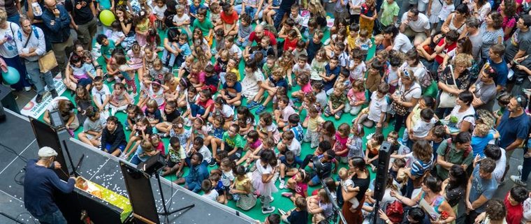 Bambini seduti in piazza davanti al palco durante La Notte Bianca dei Bambini a Genova