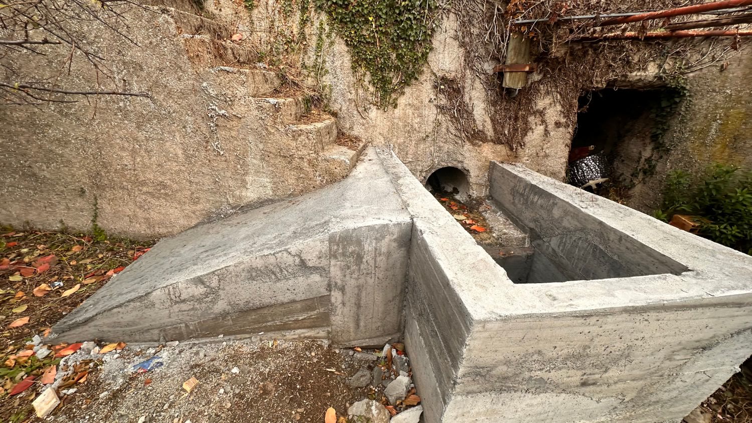 Un manufatto in cemento armato appena disarmato davanti allo sbocco di un tubo nel muro